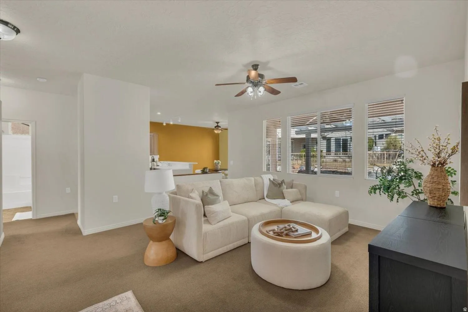 Carpeted living room featuring baseboards and a ceiling fan