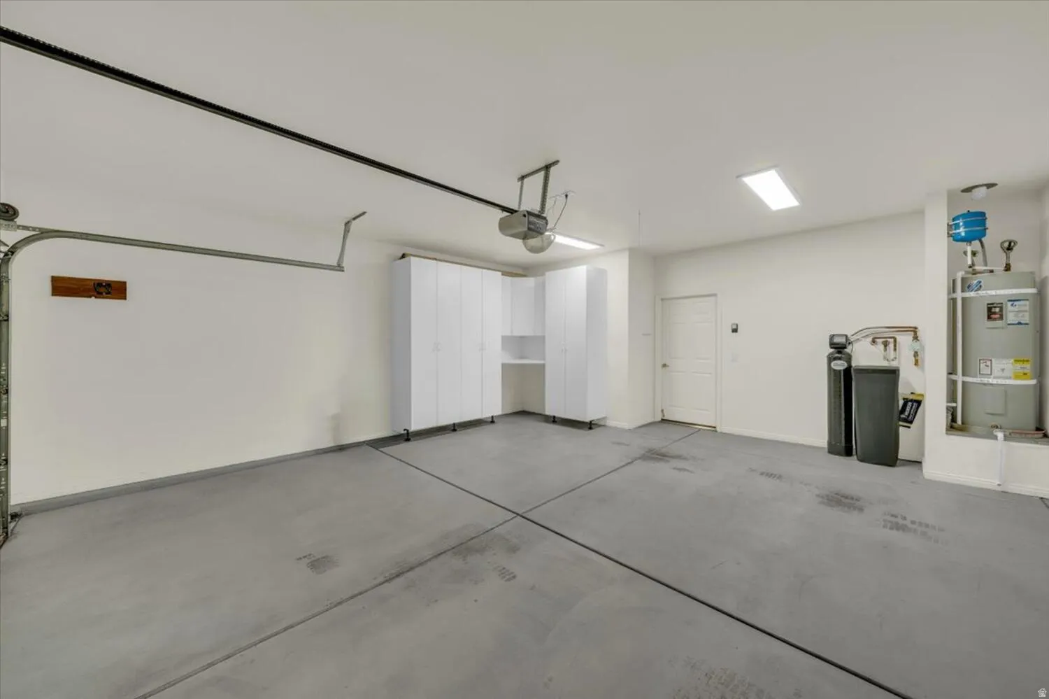 Garage featuring strapped water heater and a garage door opener