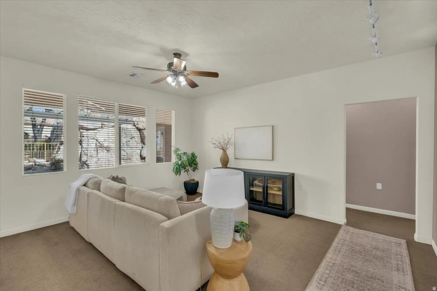 Carpeted living area featuring ceiling fan and rail lighting