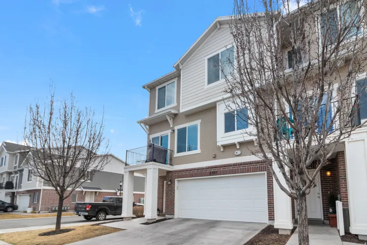 Traditional-style house with a balcony, an attached garage, concrete driveway, brick siding, and stucco siding