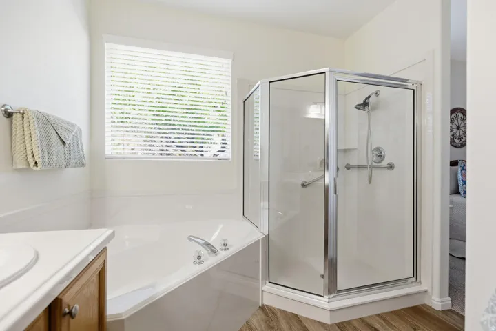 Full bathroom with vanity, a shower stall, a garden tub, and light wood-type flooring