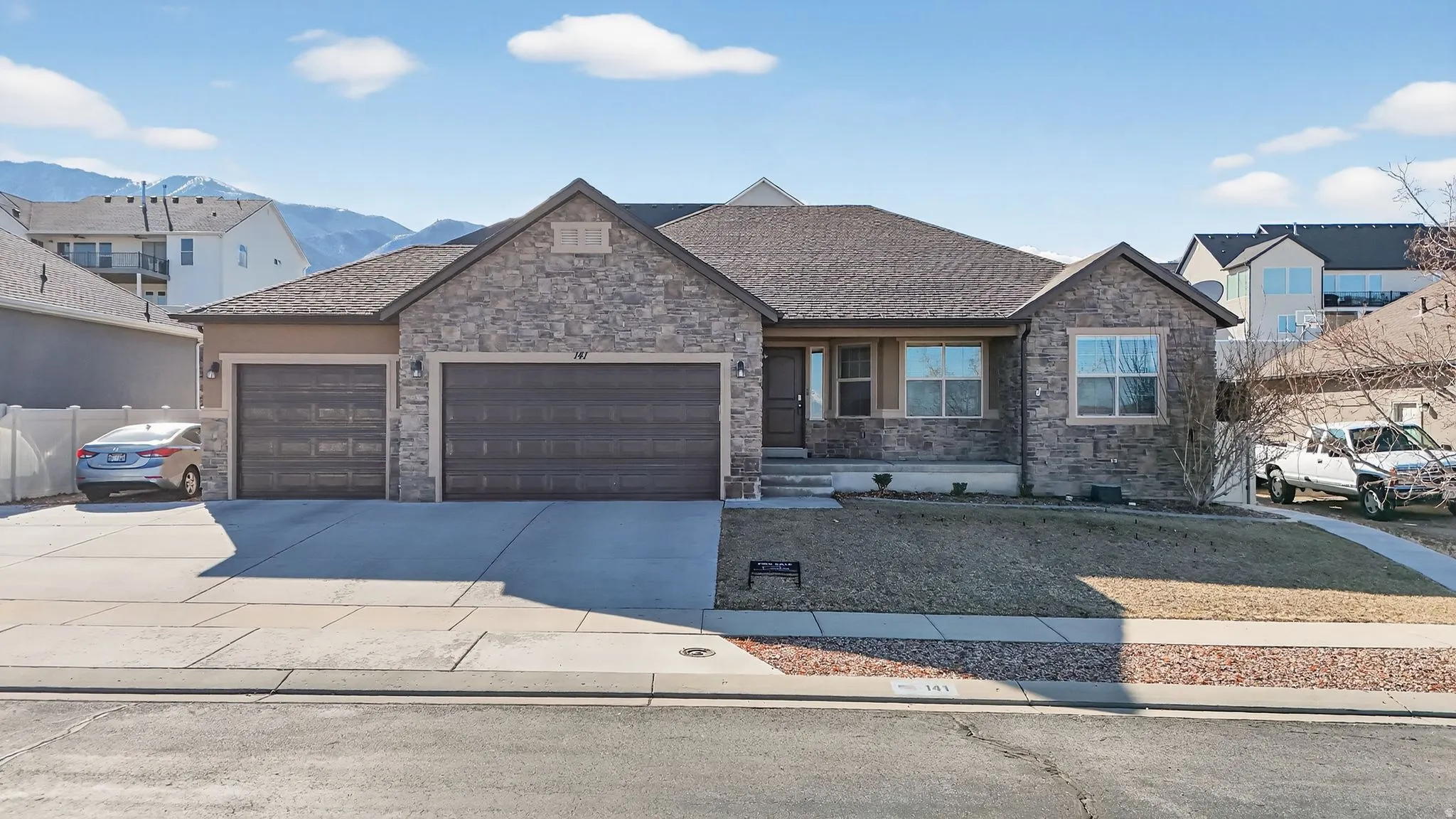 View of front of home featuring driveway, an attached garage, and stone siding