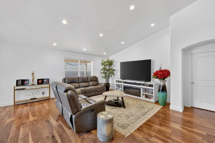 Living area featuring arched walkways, light wood finished floors, lofted ceiling, and recessed lighting