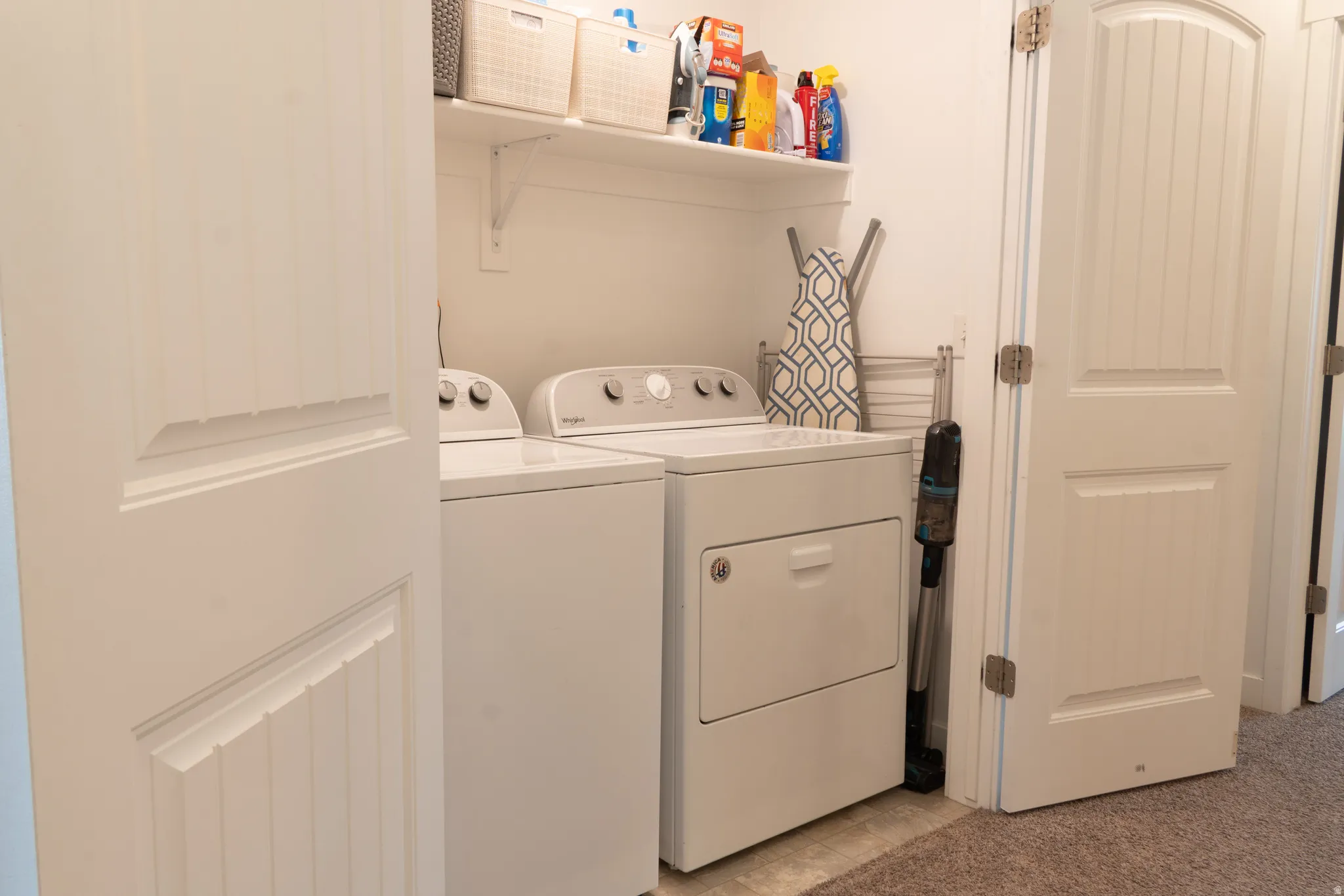 Laundry area featuring washing machine and dryer and light colored carpet