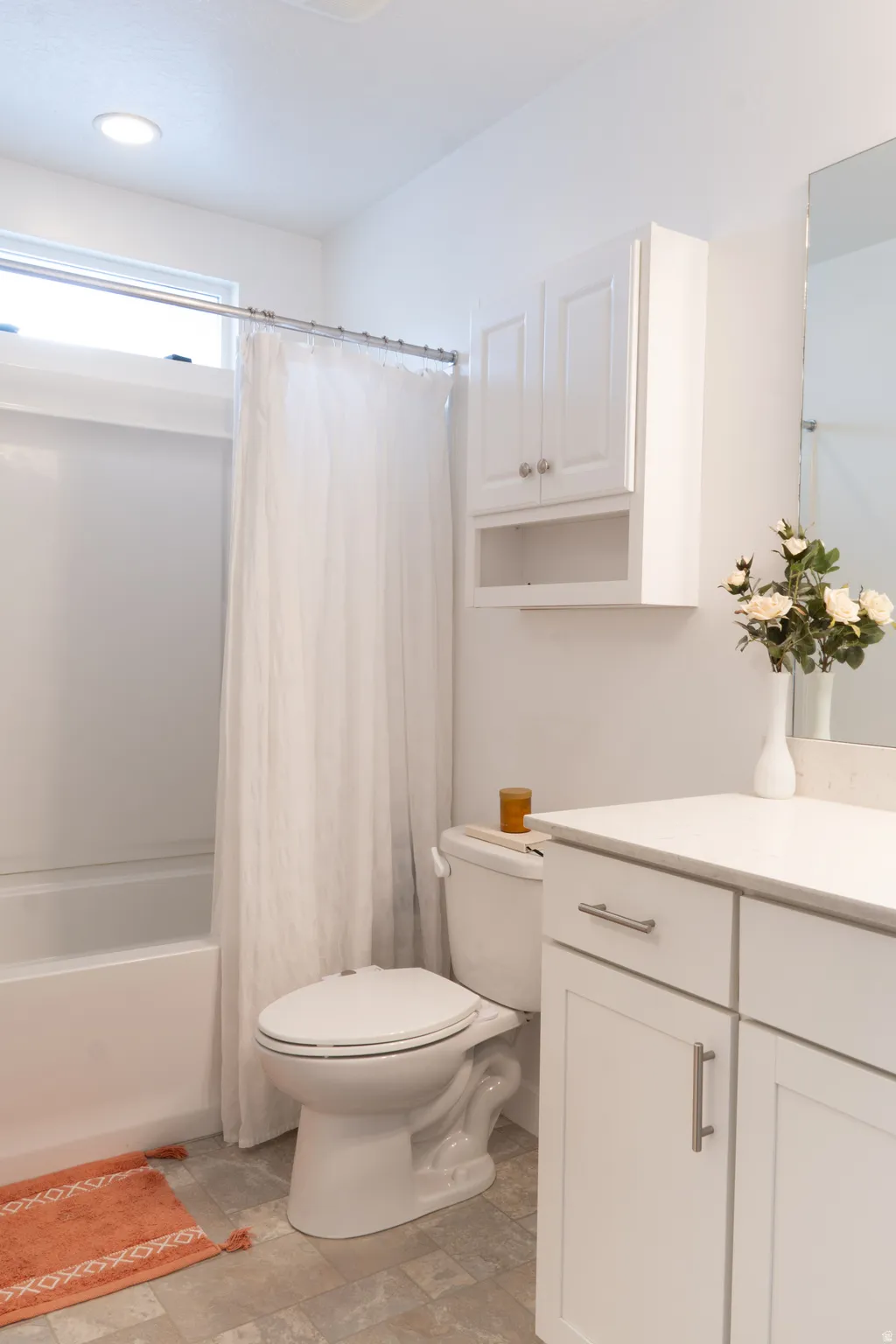Bathroom with vanity, shower / bath combo, and stone finish flooring