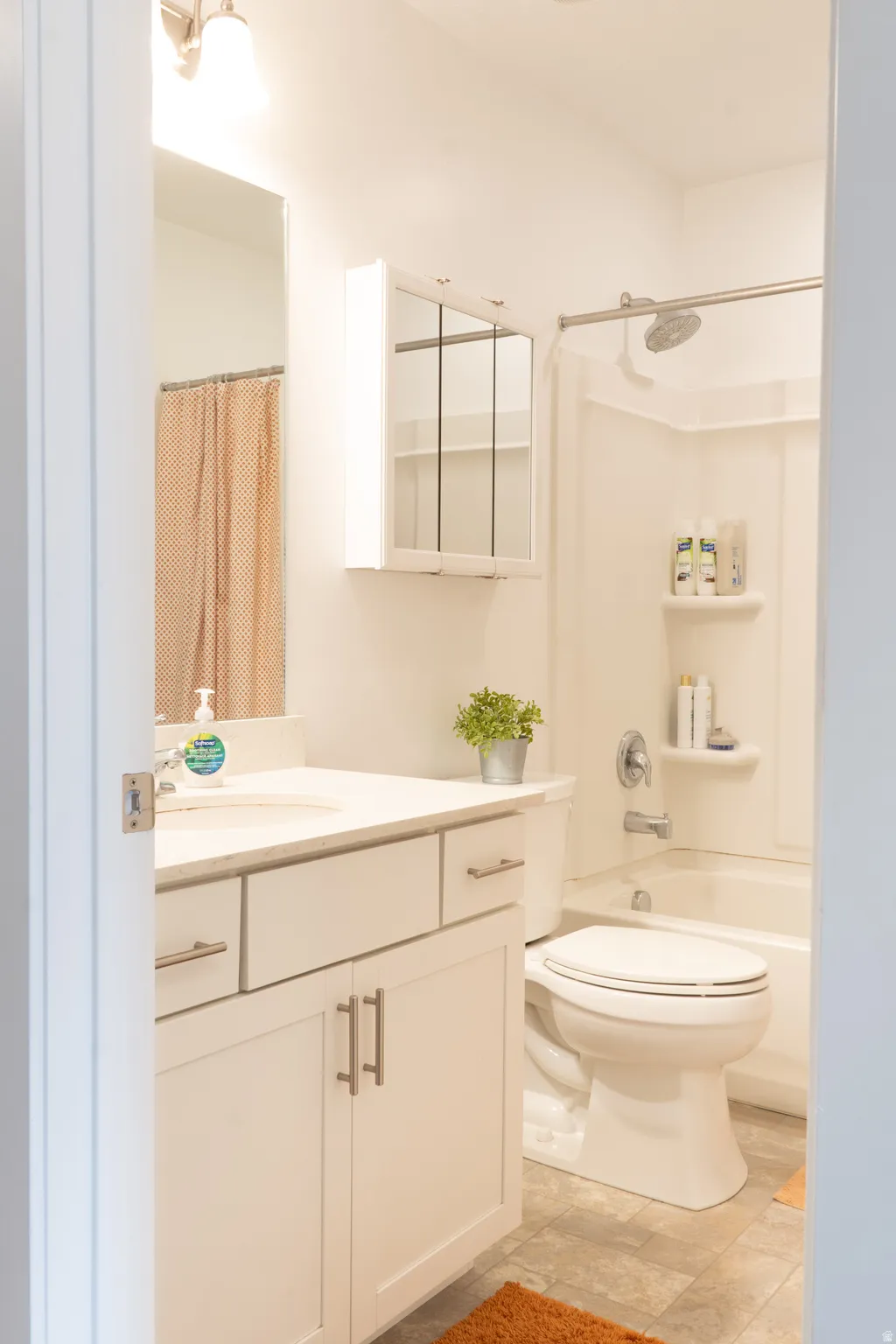 Bathroom featuring vanity and shower / bathtub combination with curtain