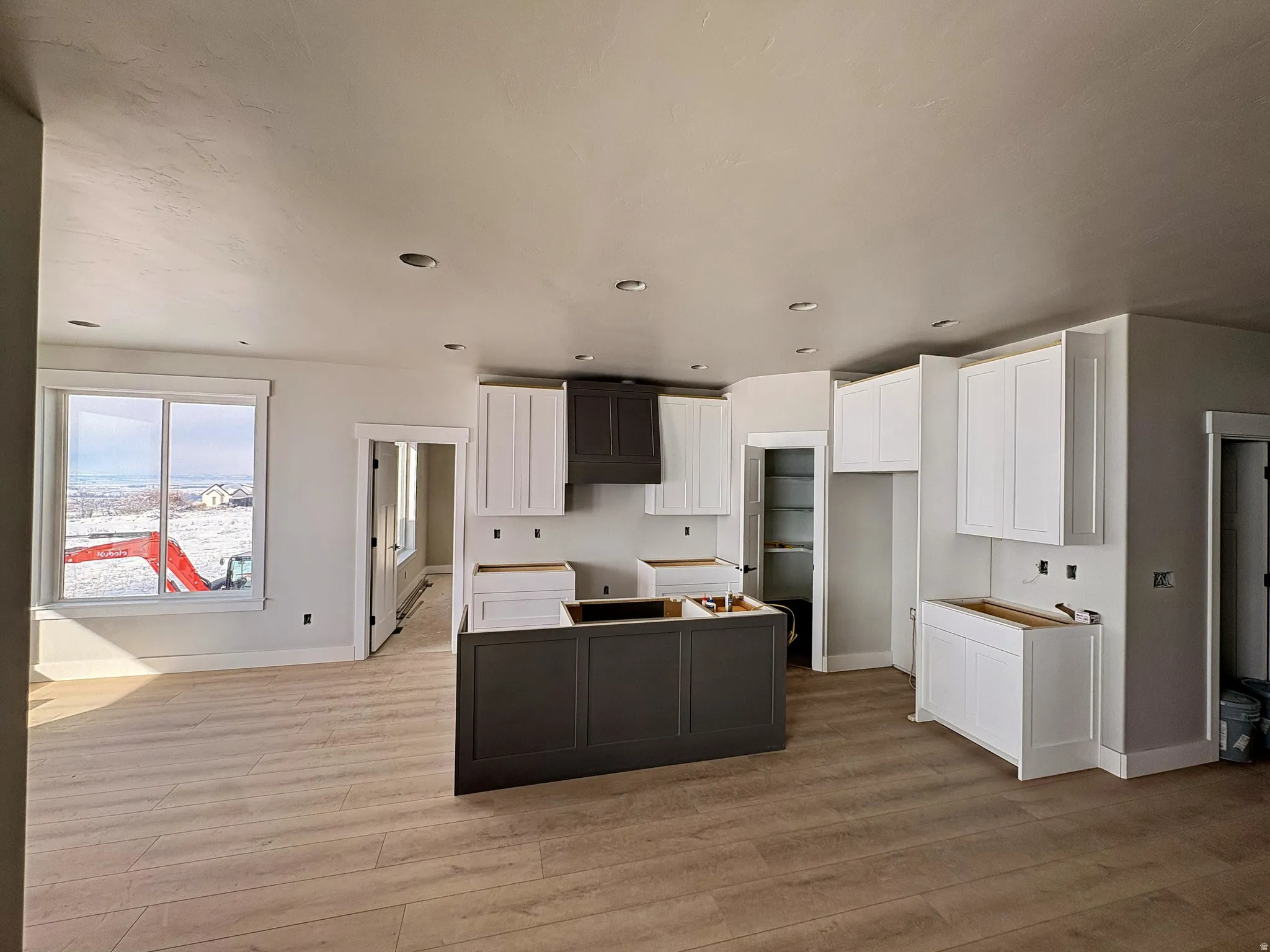 Dual tone kitchen with a center island, two tone color scheme, light wood-type flooring, and recessed lighting