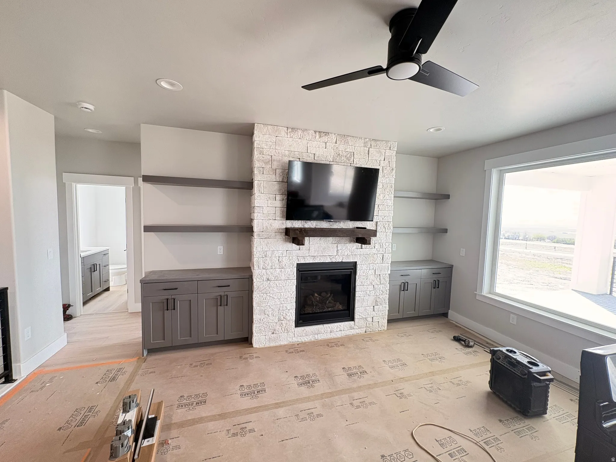 Unfurnished living room featuring a fireplace and ceiling fan