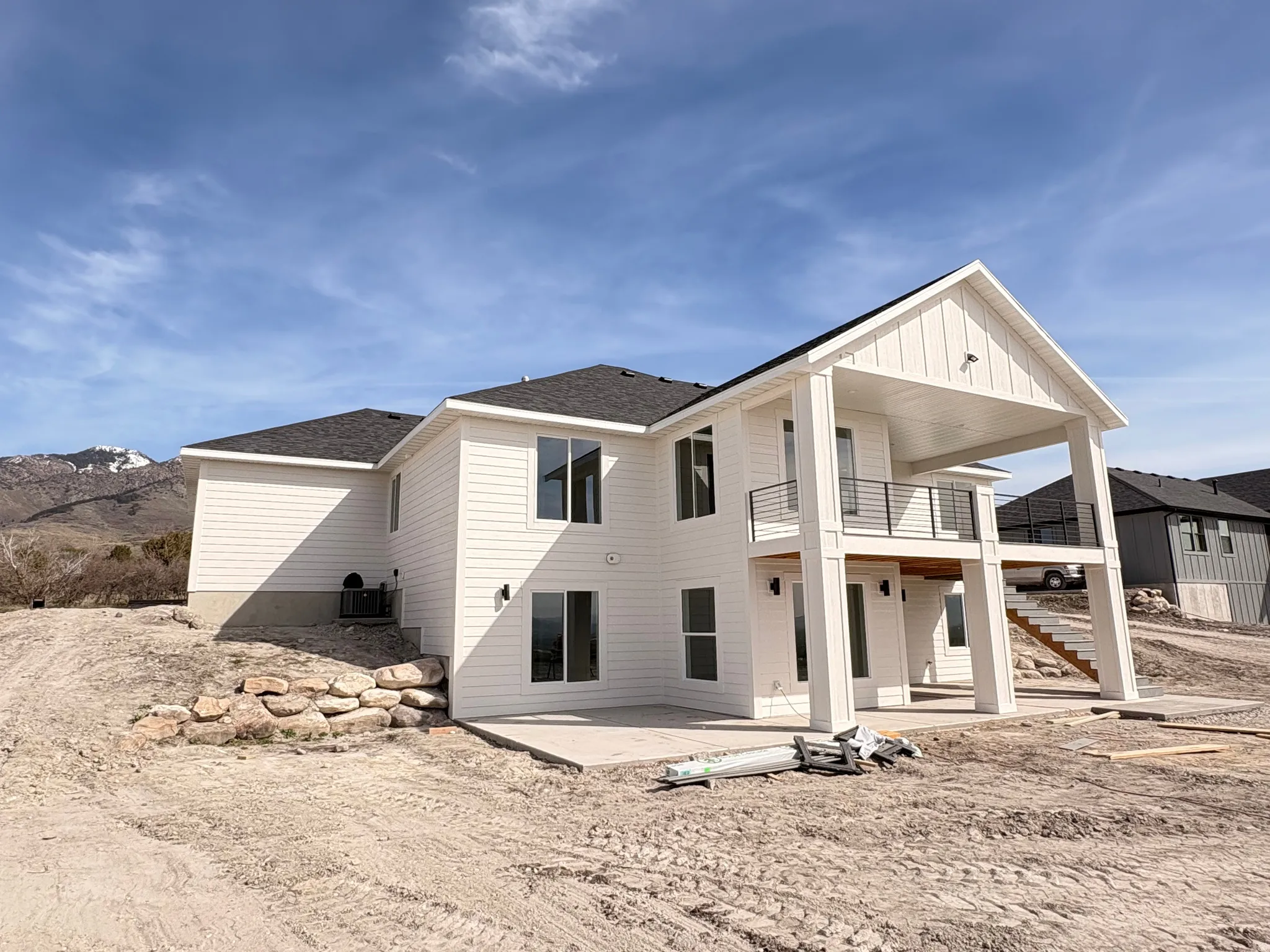 Back of house featuring a patio area, board and batten siding, a shingled roof, and a balcony