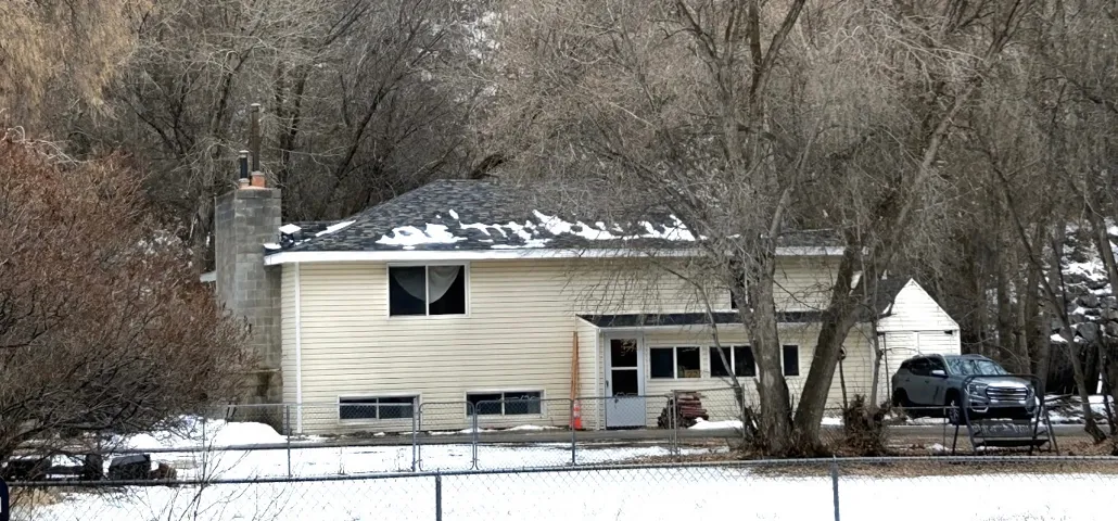 Snow covered rear of property with a fenced front yard and a chimney