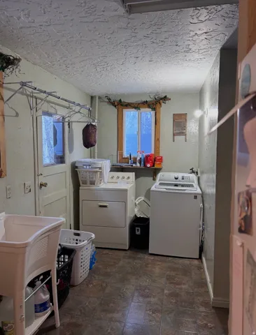 Laundry area with washer and dryer and dark stone finish flooring