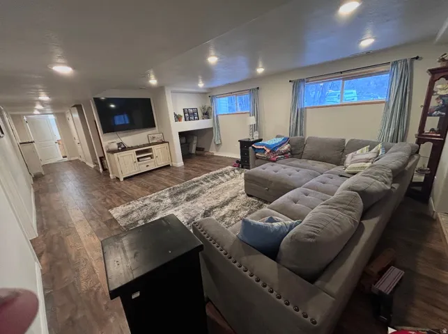 Living area with dark wood-type flooring and recessed lighting