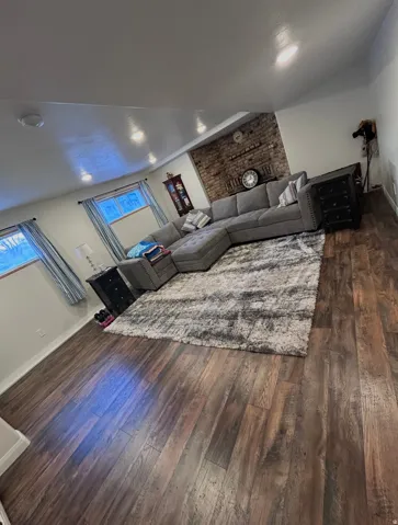 Living room with dark wood-type flooring and a brick fireplace
