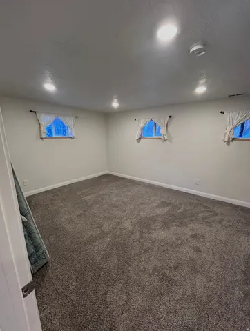 Basement with dark carpet, a textured ceiling, and healthy amount of natural light