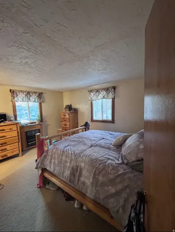 Bedroom featuring light carpet and a textured ceiling