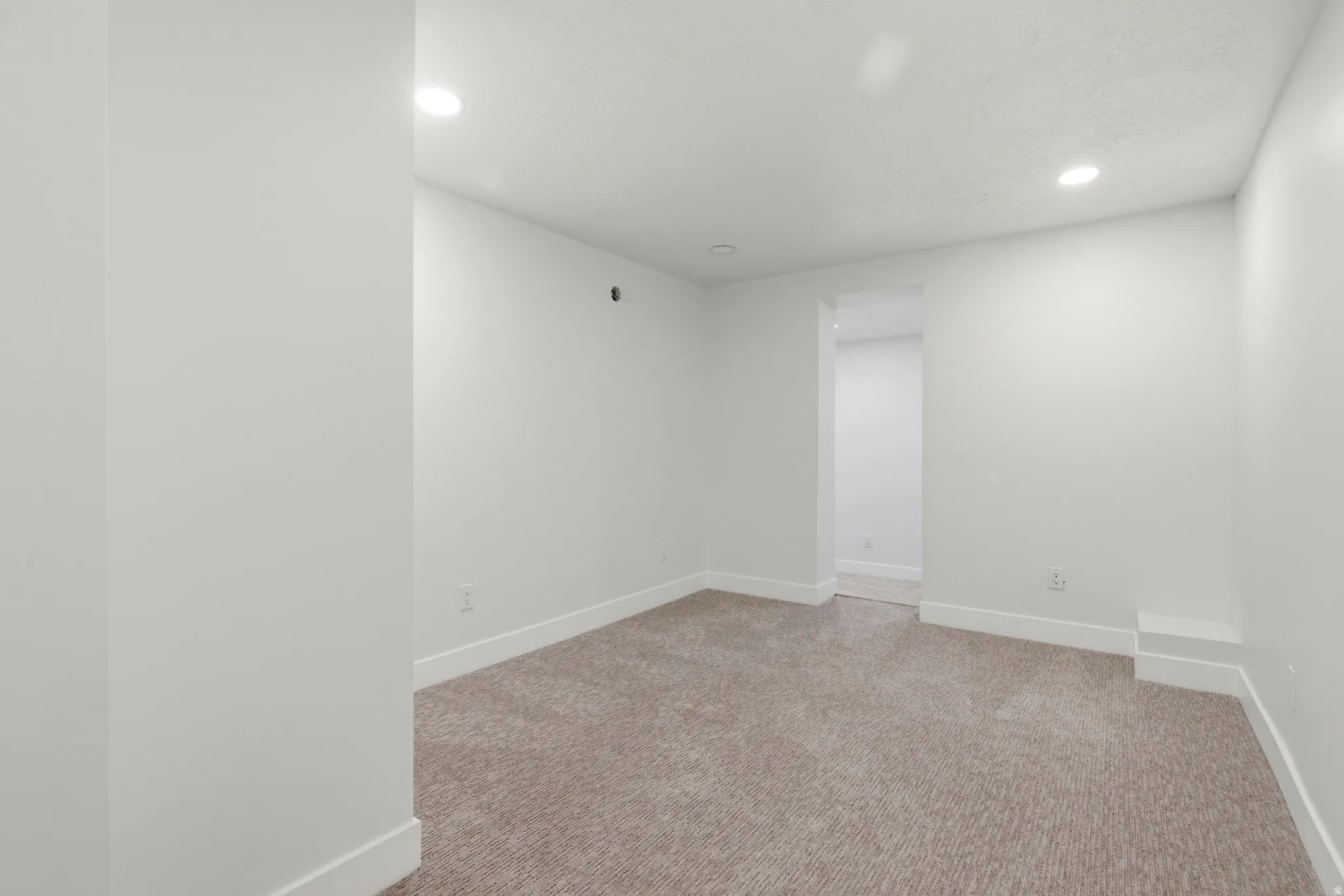 Empty room featuring recessed lighting and light carpet