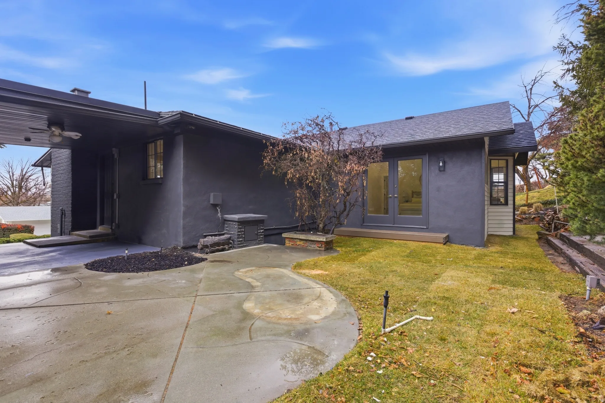 Rear view of property with french doors, stucco siding, a lawn, and roof with shingles