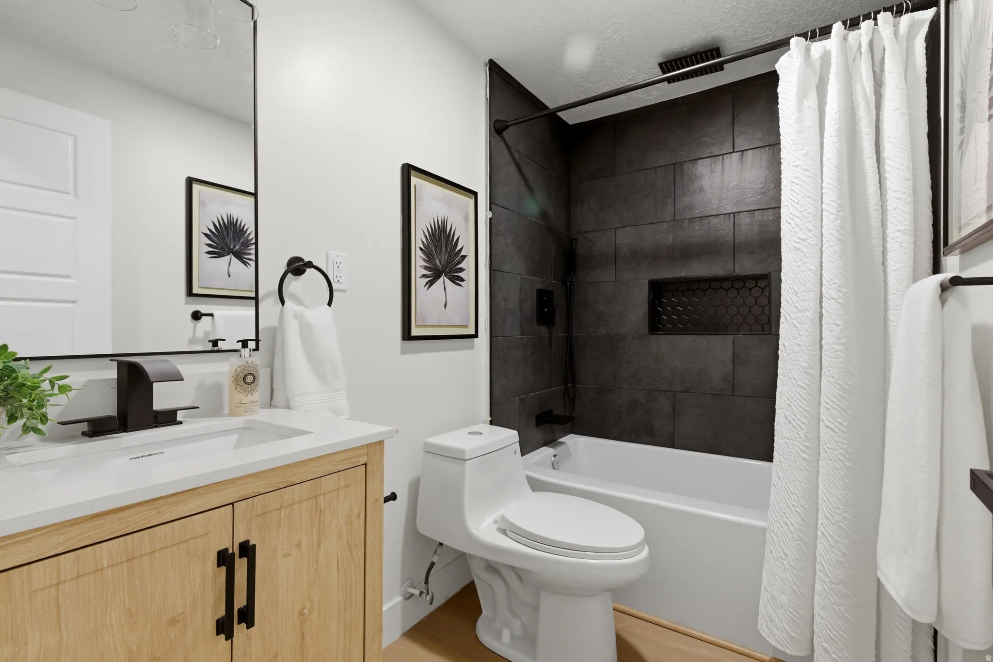 Full bathroom with a combined bath / shower with rainfall shower, vanity, a textured ceiling, and light wood-style flooring