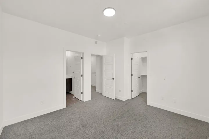 Unfurnished bedroom featuring a walk in closet, carpet floors, and connected bathroom