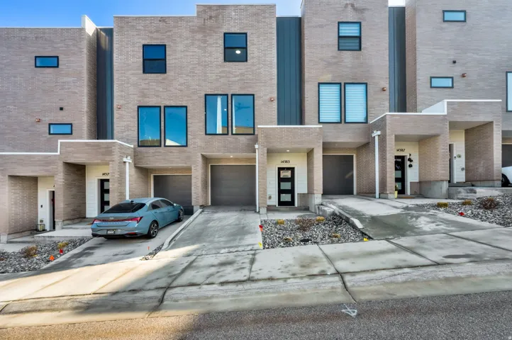 Contemporary home with an attached garage, brick siding, and driveway