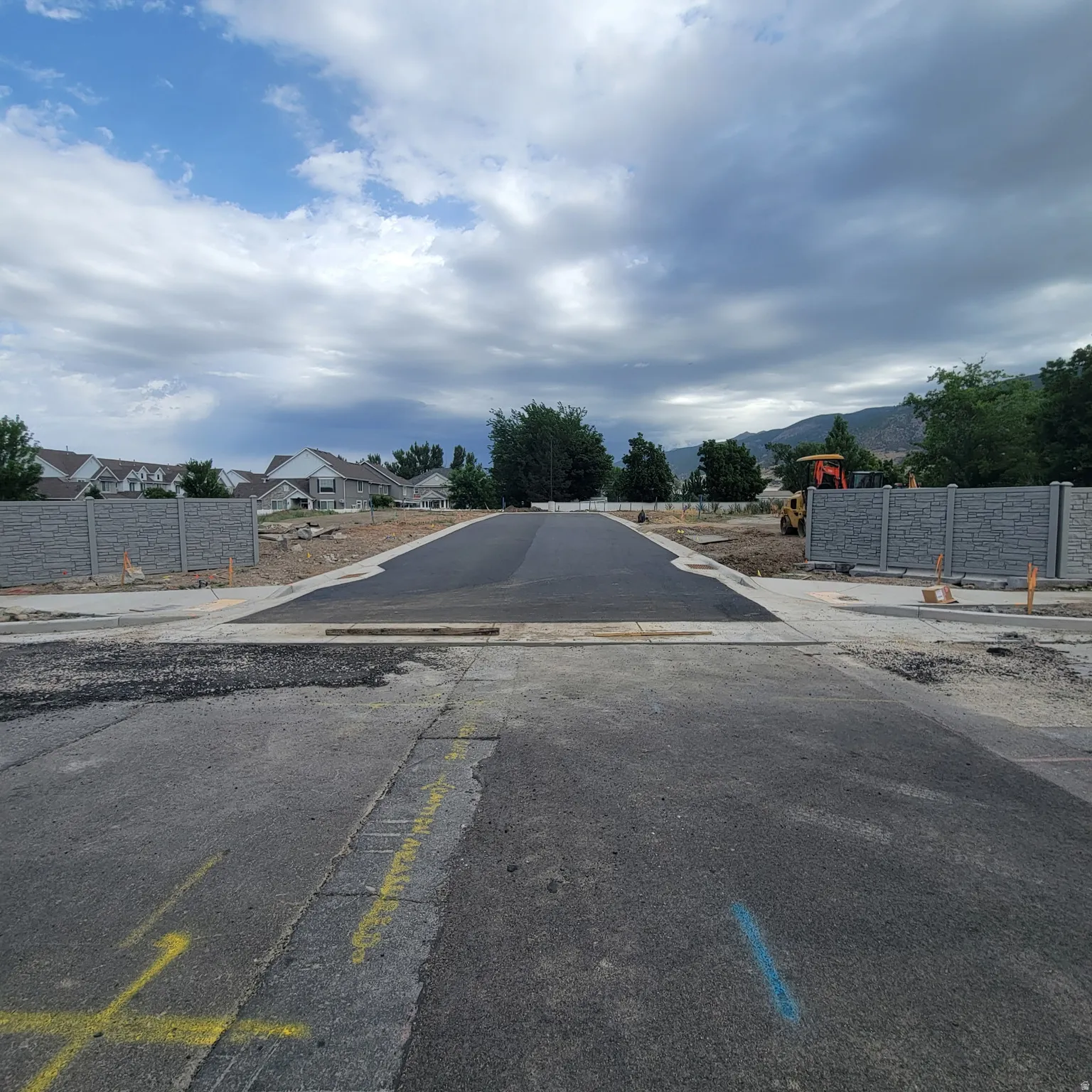 Newly paved asphalt roadway leading into a developing community