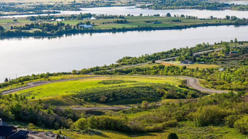 Expansive water body with verdant tree-lined shores, surrounded by agricultural fields and distant hills
