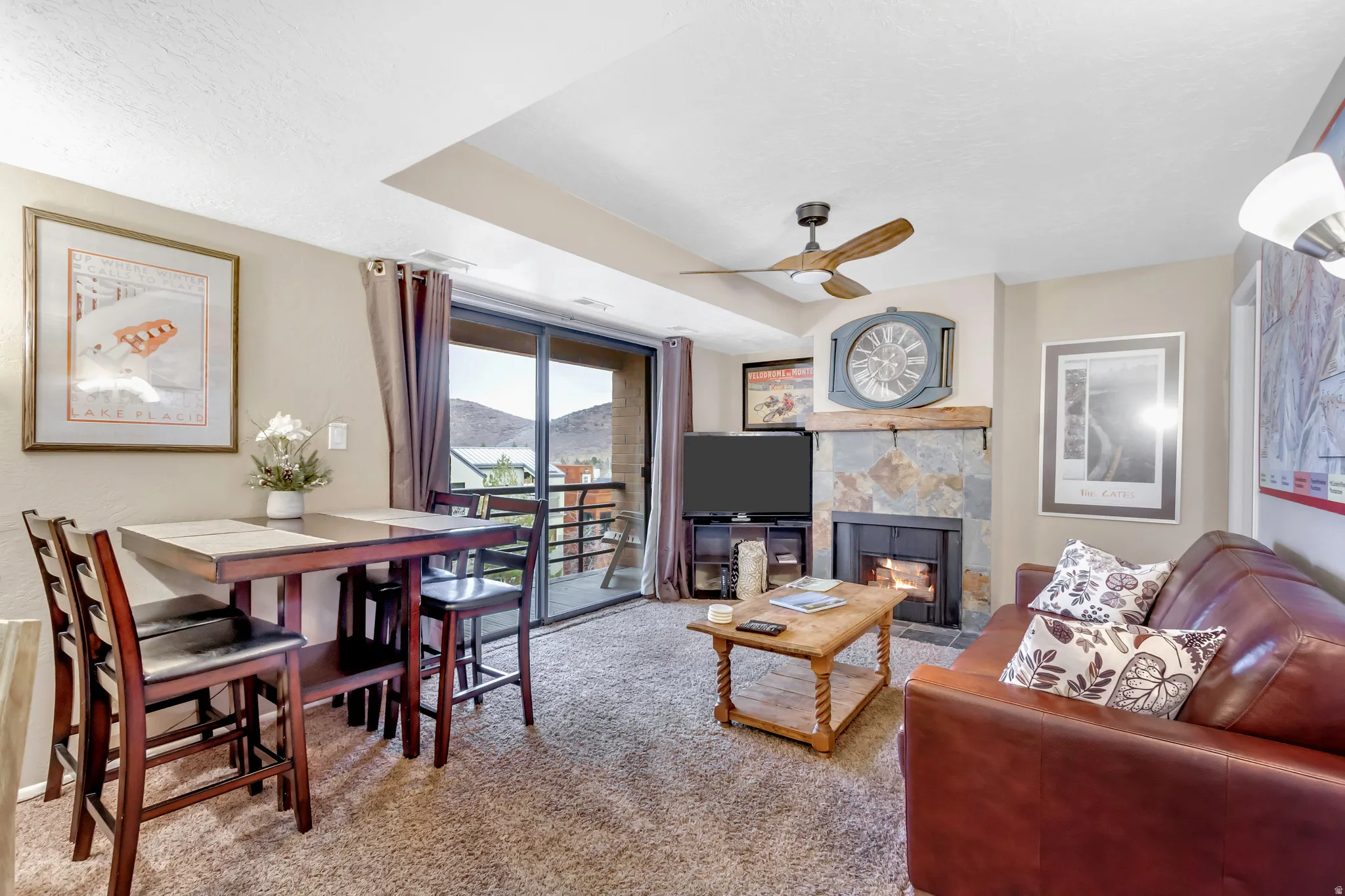 Living room with a tile fireplace, light colored carpet, ceiling fan, and a textured ceiling