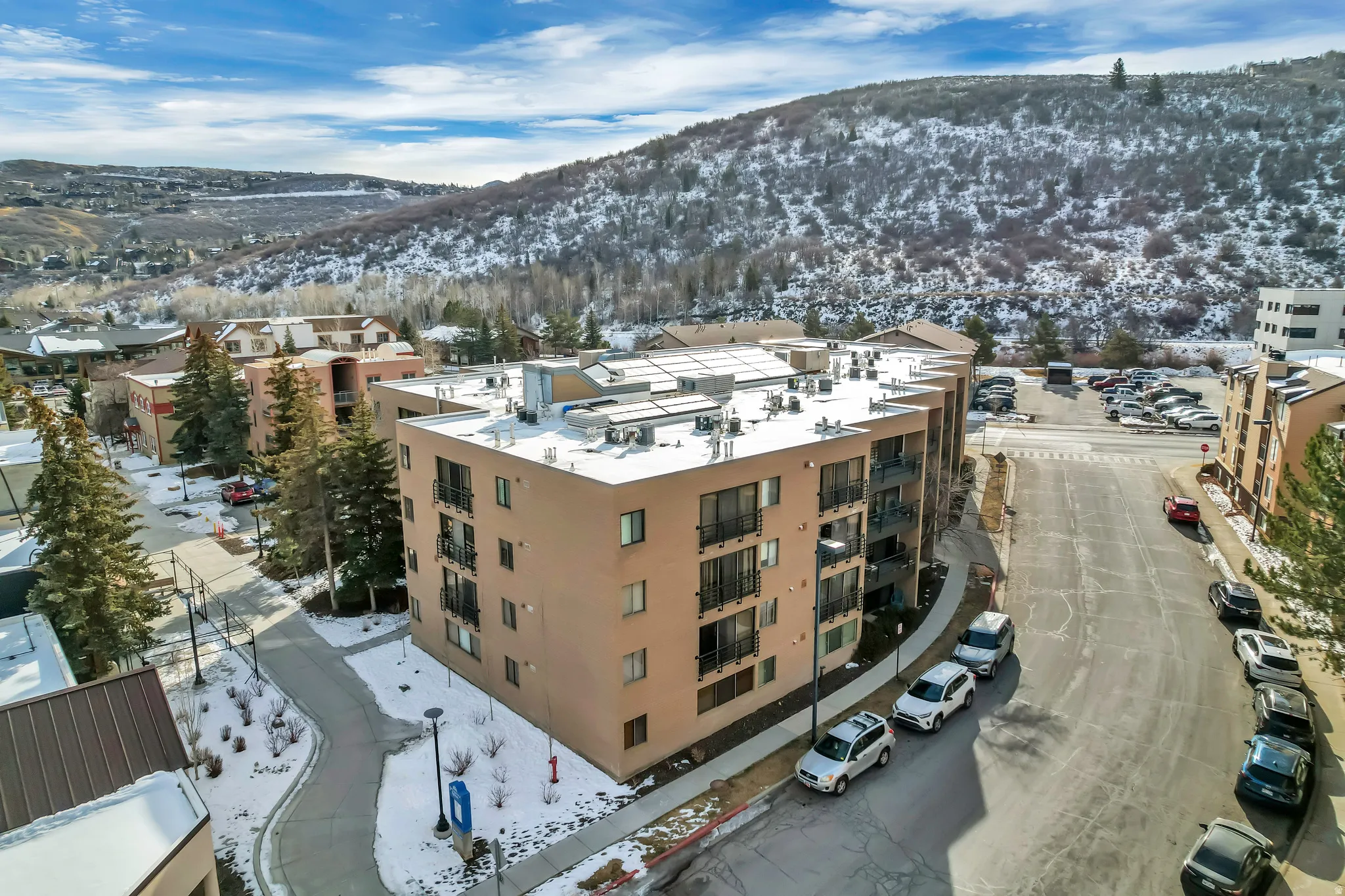 Snowy aerial view featuring a mountain view and a view of apartment building / complex