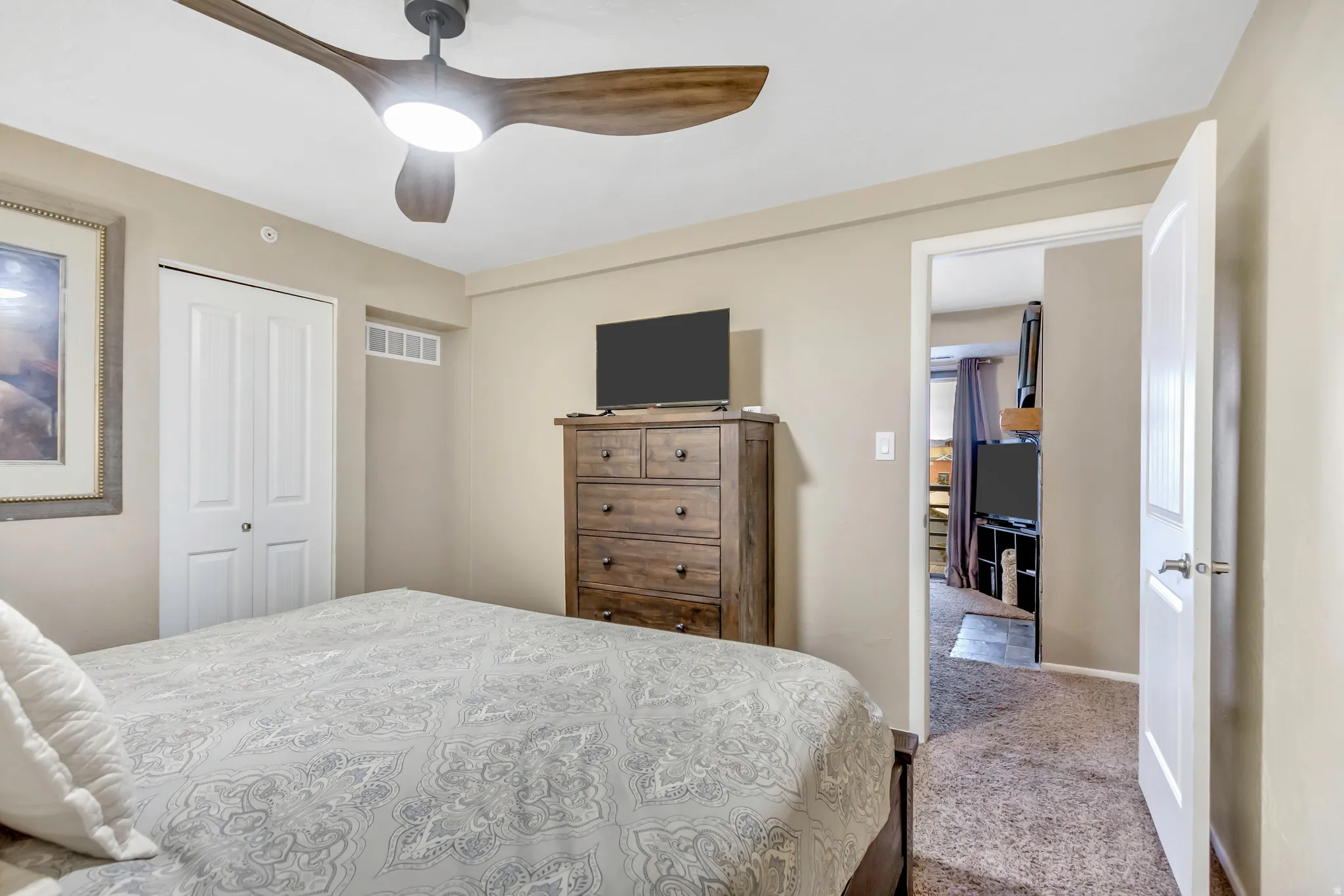 Carpeted bedroom with a closet and a ceiling fan