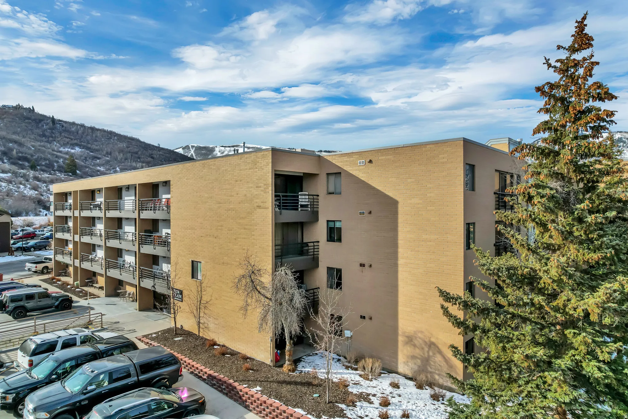 Snow covered building featuring a view of apartment building / complex and a mountain view