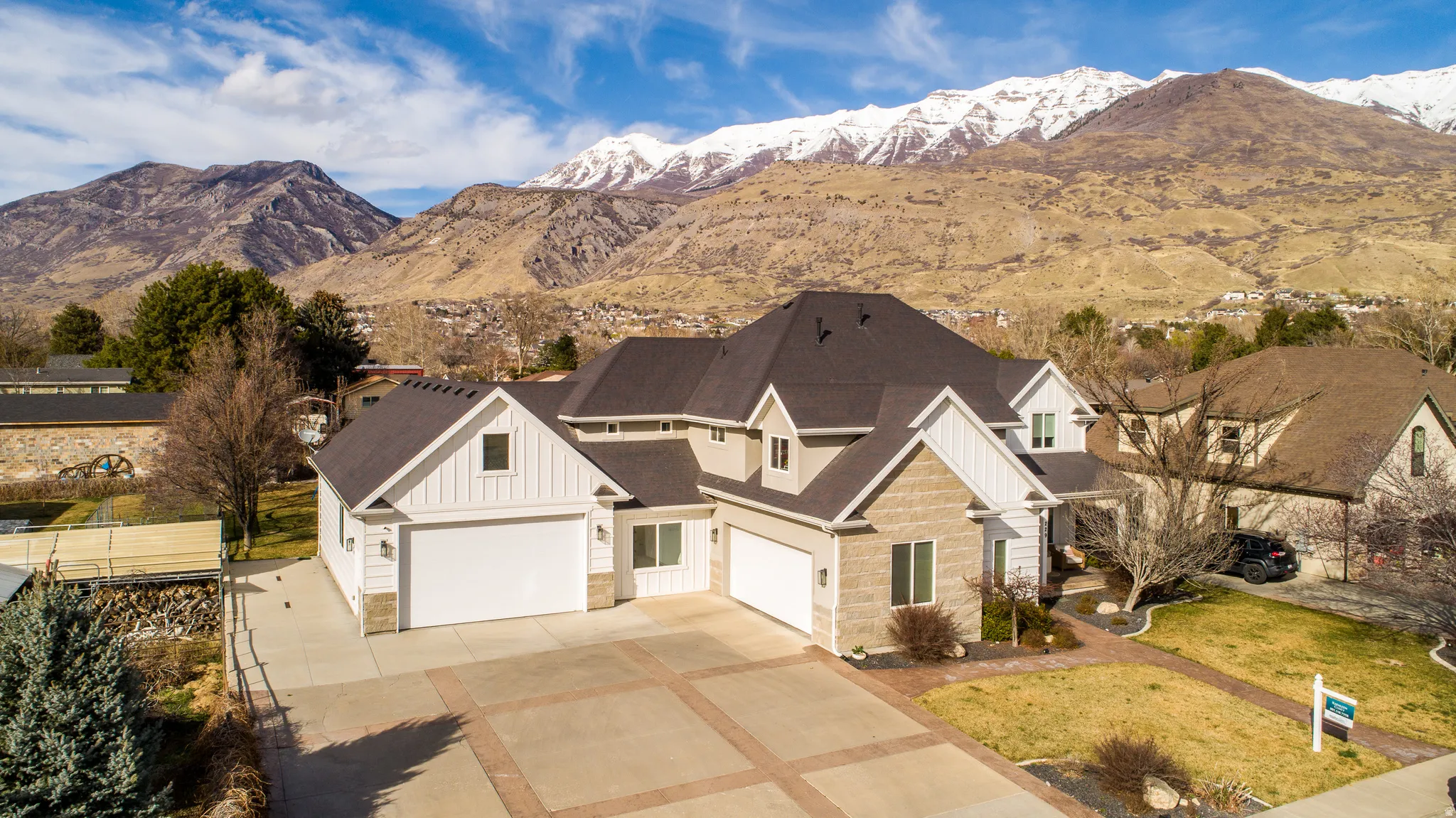 View of front facade with board and batten siding, stone siding, driveway, and a mountain view