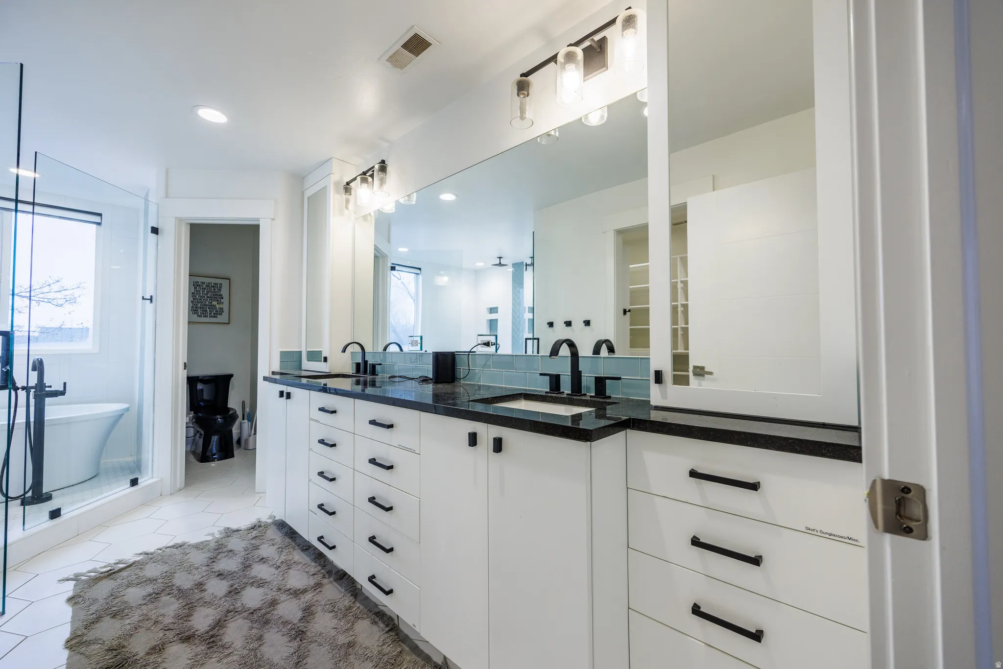 Bathroom with double vanity, light tile patterned flooring, a freestanding tub, and recessed lighting