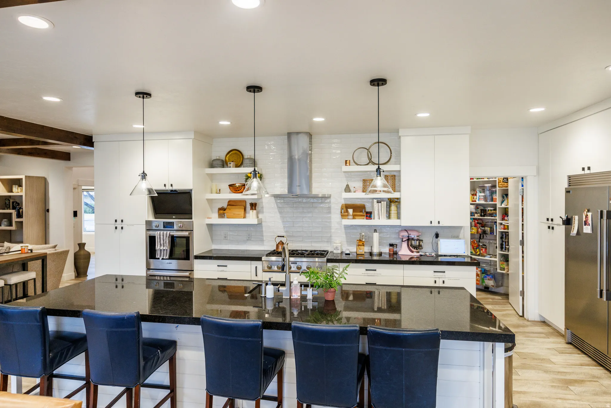 Kitchen with open shelves, white cabinets, decorative light fixtures, a breakfast bar, and stainless steel appliances