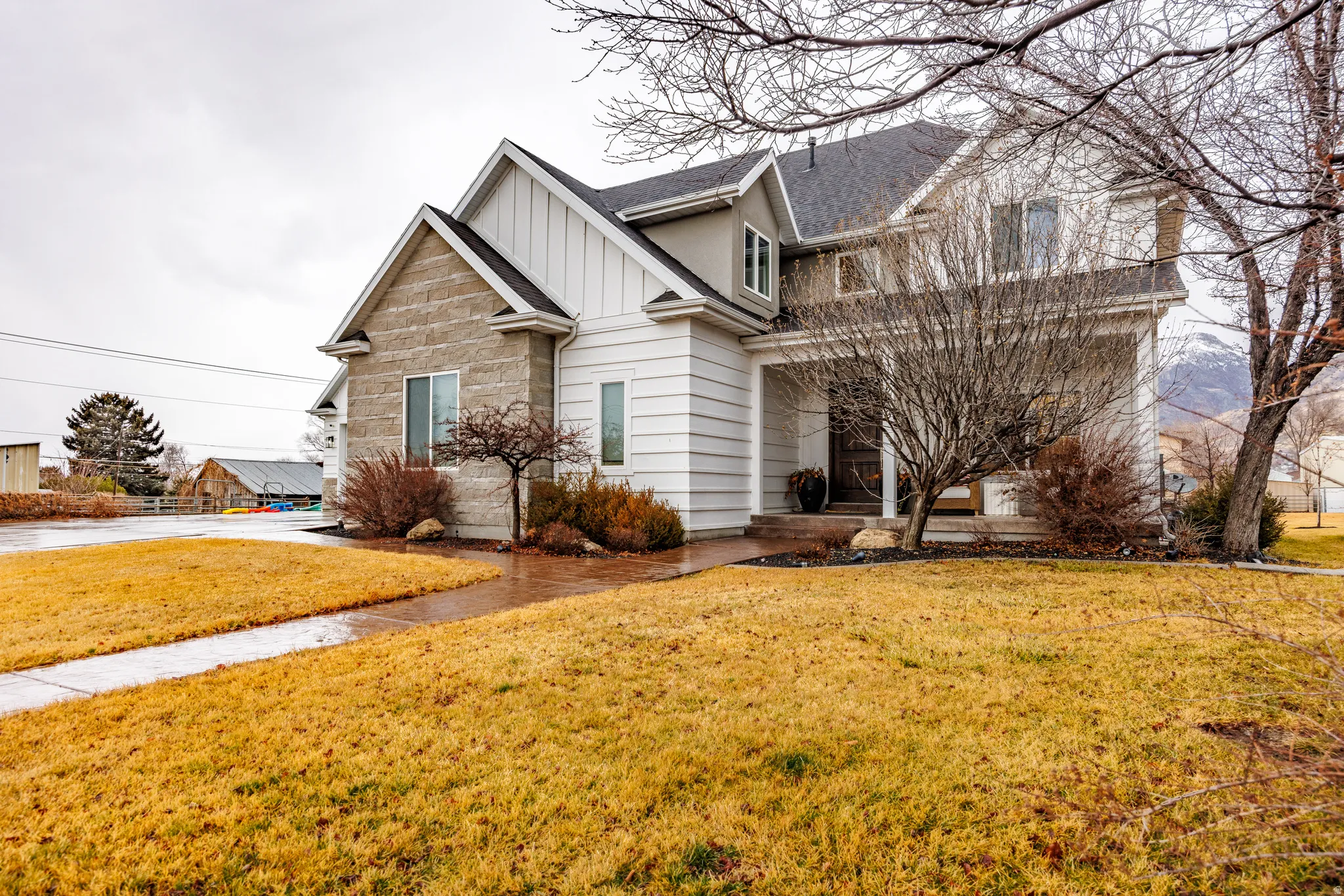 View of front facade with board and batten siding, a front yard, a shingled roof, and a porch