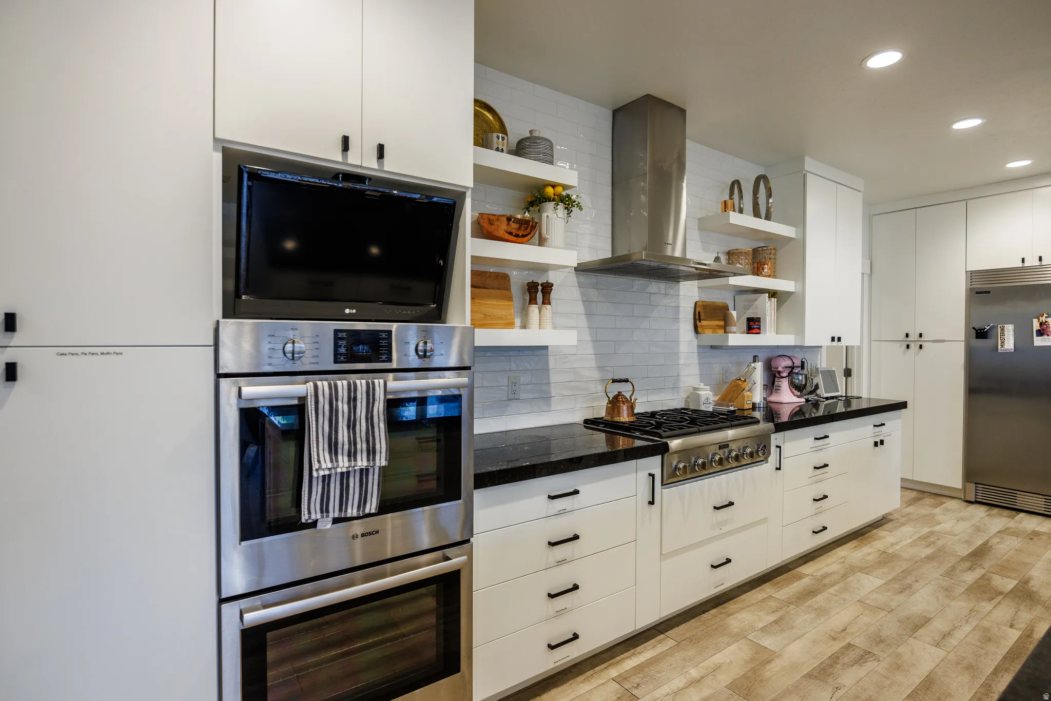 Kitchen with open shelves, exhaust hood, stainless steel appliances, recessed lighting, and white cabinets