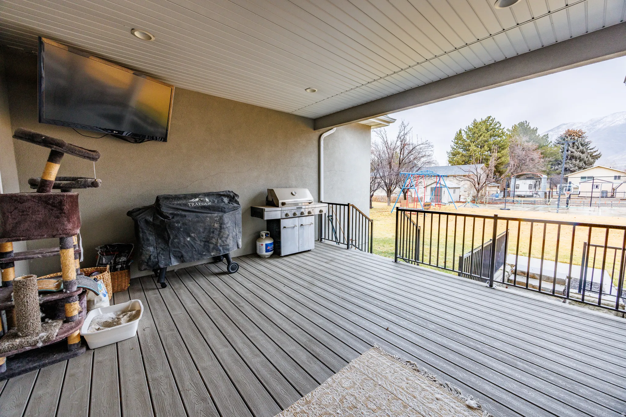 Wooden terrace featuring area for grilling, a yard, and a playground