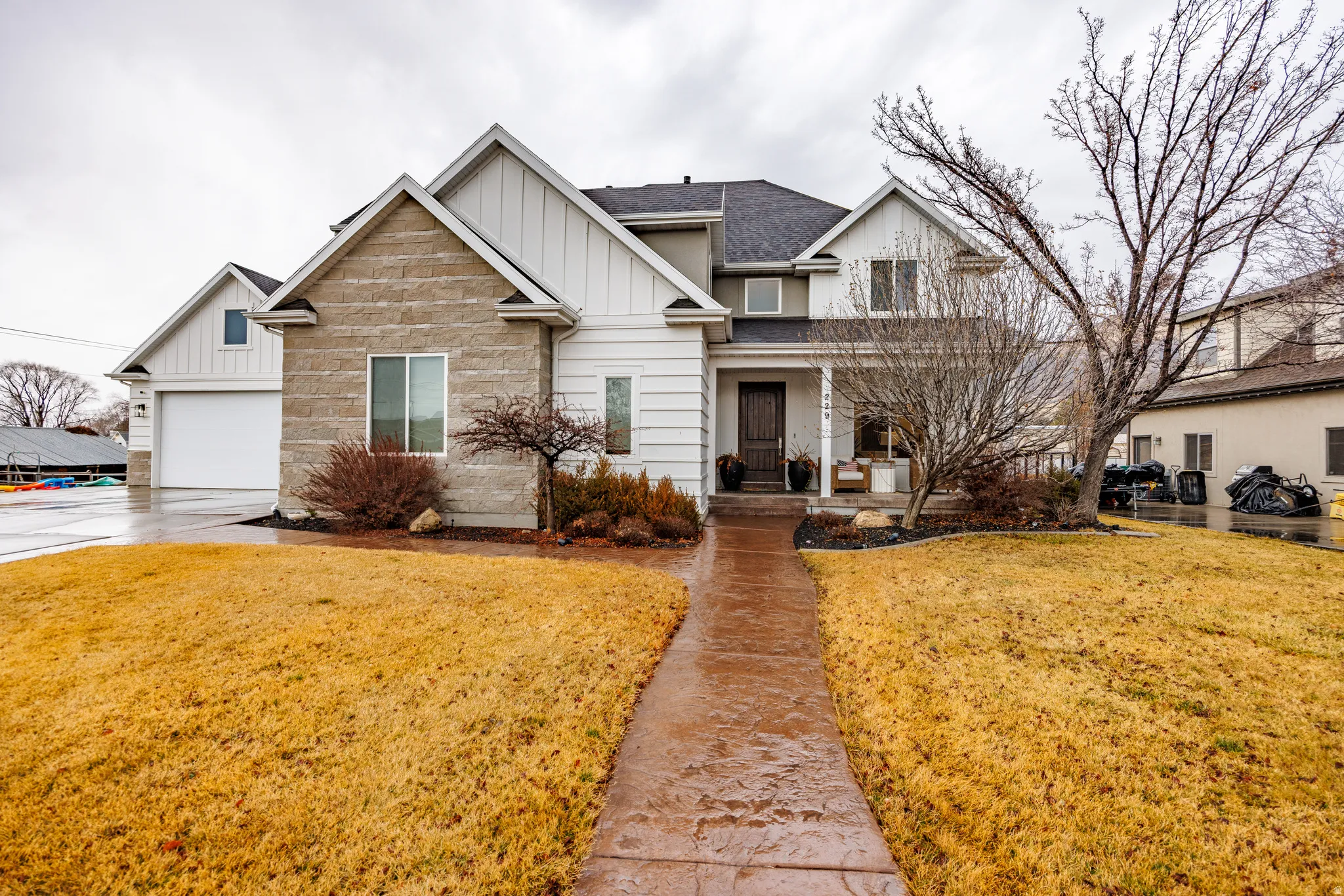 View of front of home featuring board and batten siding, a front yard, roof with shingles, and stone siding