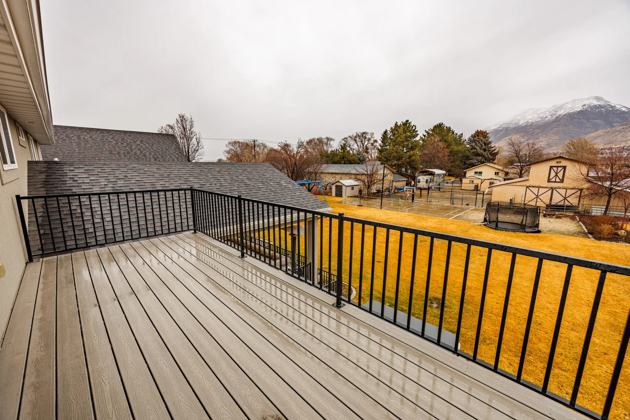 Wooden deck with a trampoline, an outdoor structure, and a residential view
