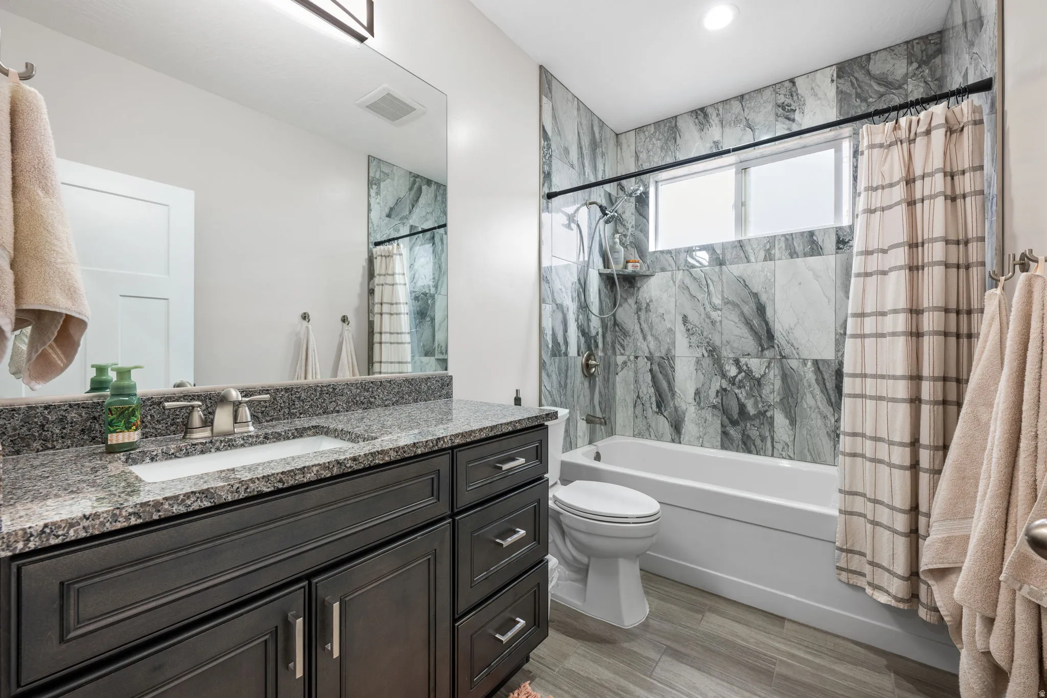 Full bath with vanity, shower / bathtub combination with curtain, and light wood-type flooring