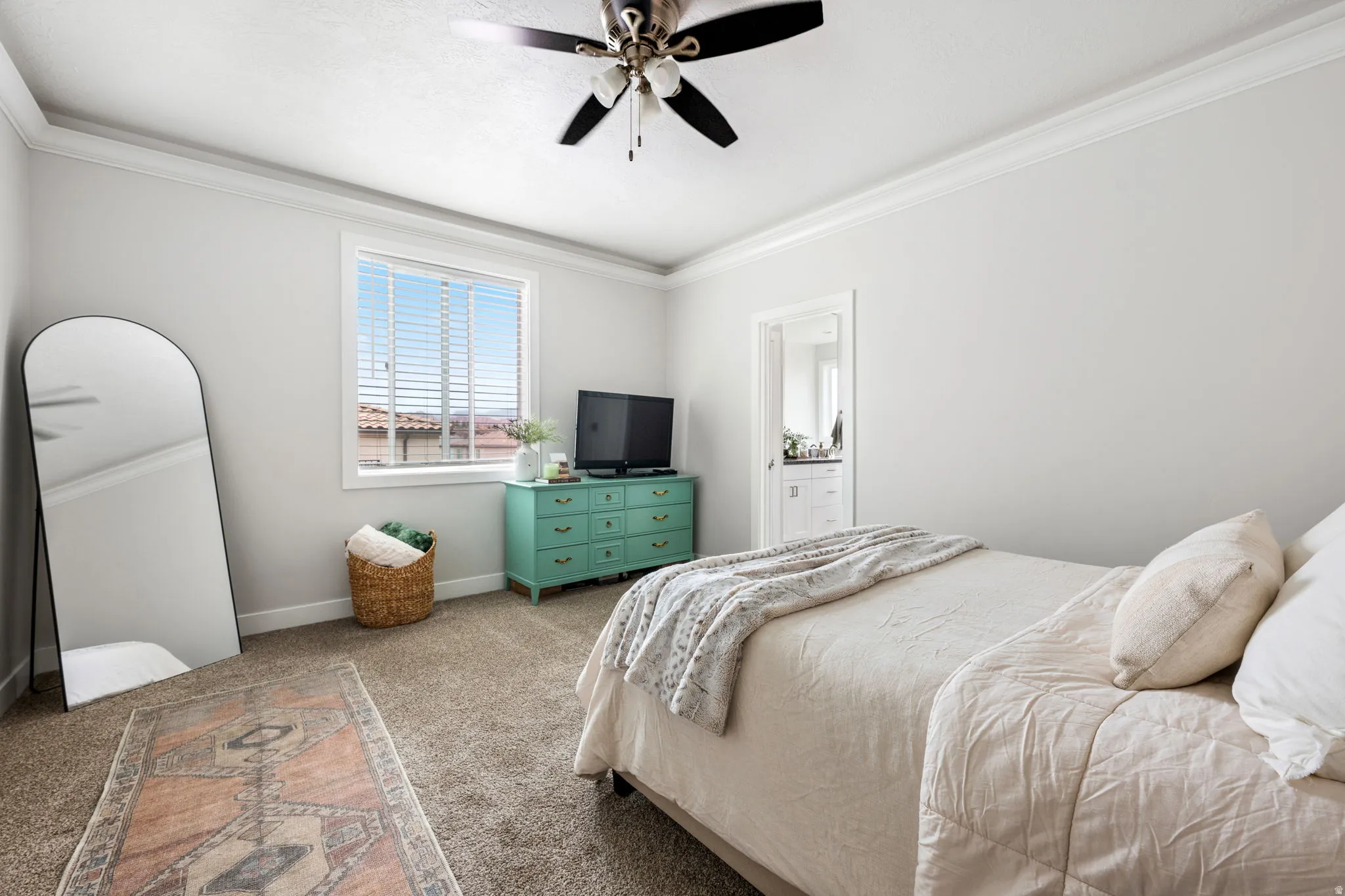Carpeted bedroom with crown molding, ceiling fan, and ensuite bathroom