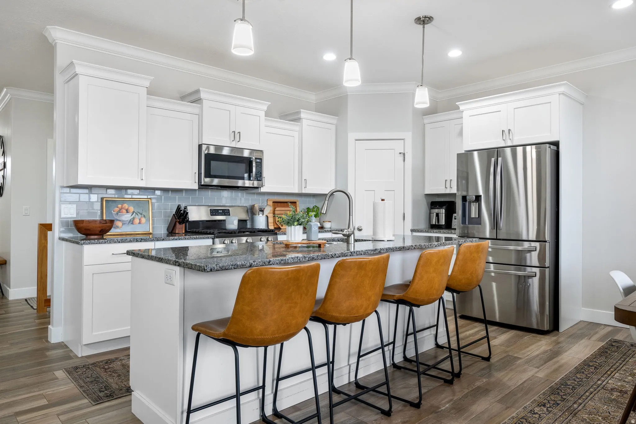Kitchen featuring a kitchen island with sink, dark stone countertops, stainless steel appliances, ornamental molding, and a breakfast bar