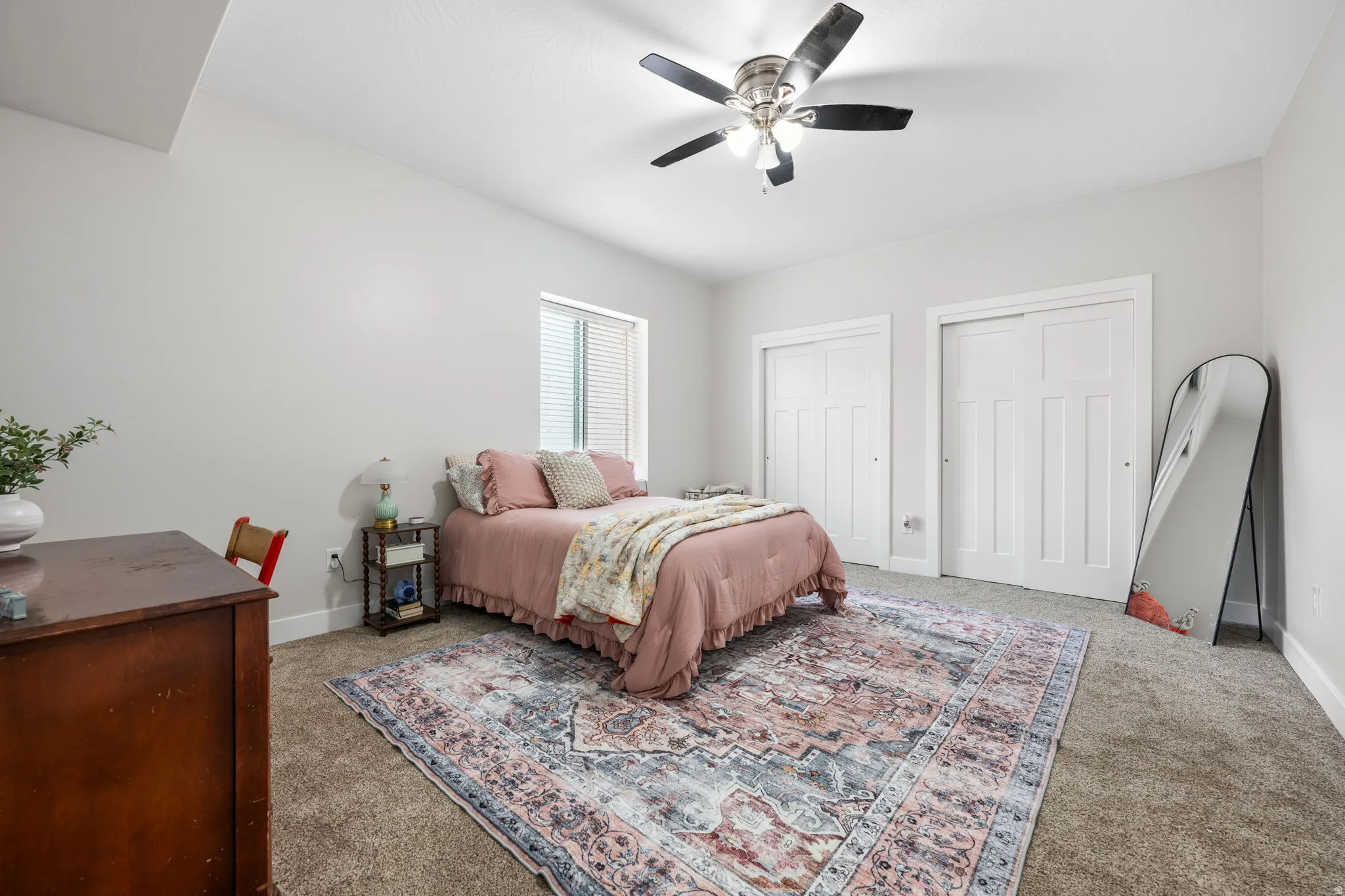 Carpeted bedroom with two closets and a ceiling fan