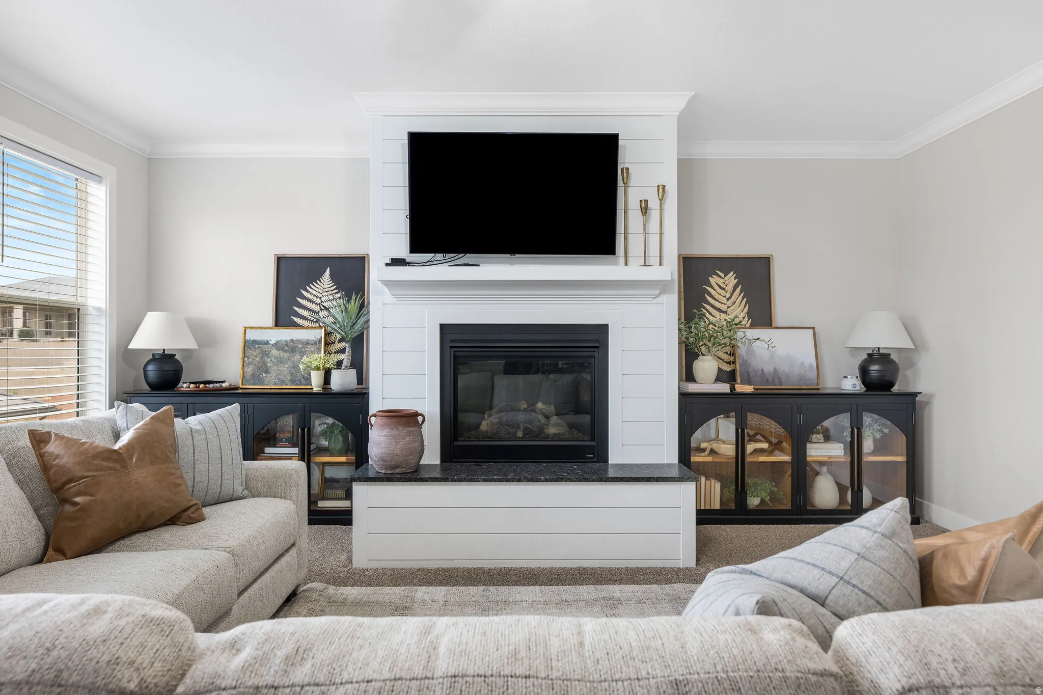Living room with ornamental molding, a large fireplace, and carpet flooring