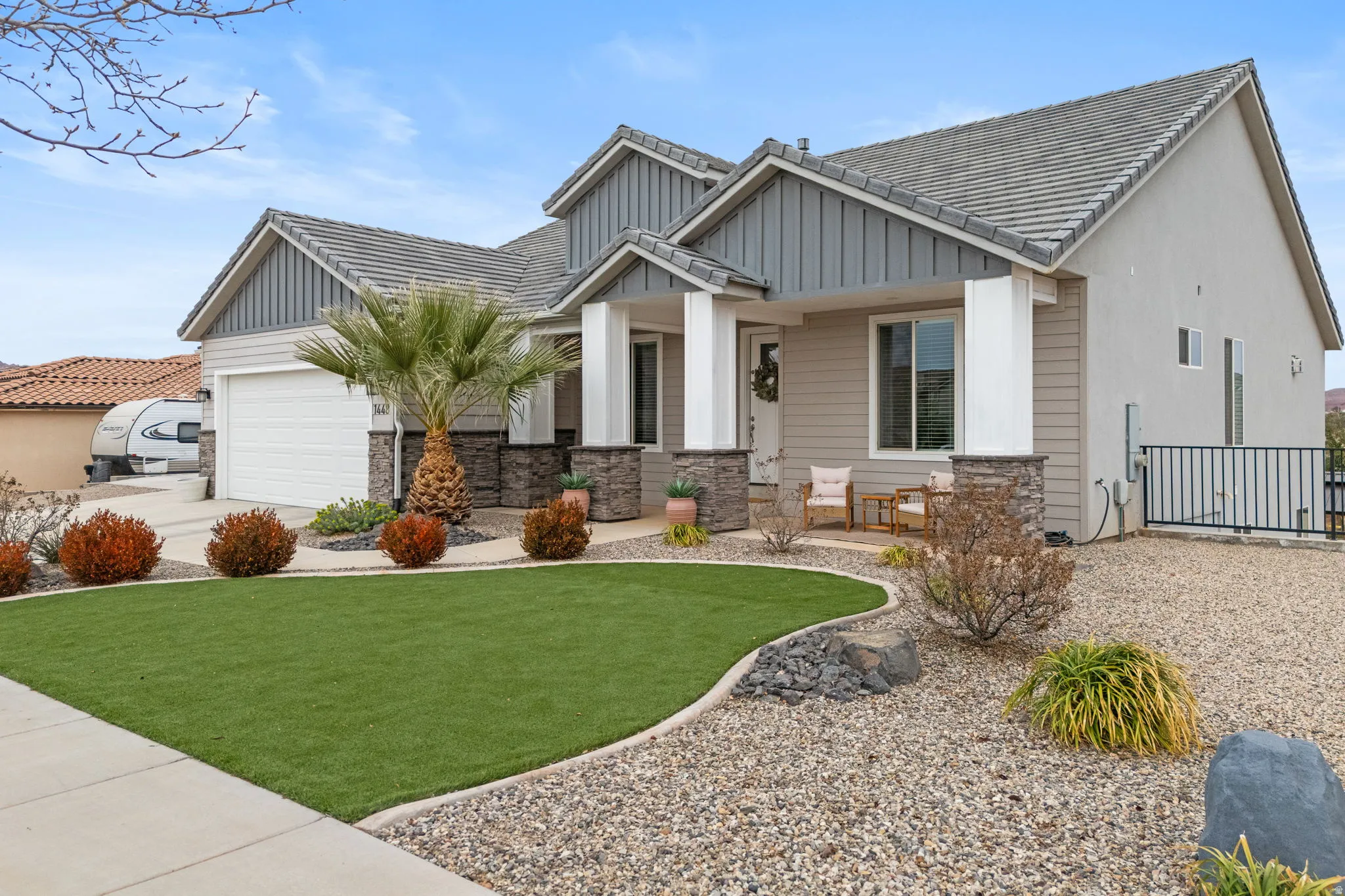 View of front of property featuring an attached garage, board and batten siding, driveway, and stone siding