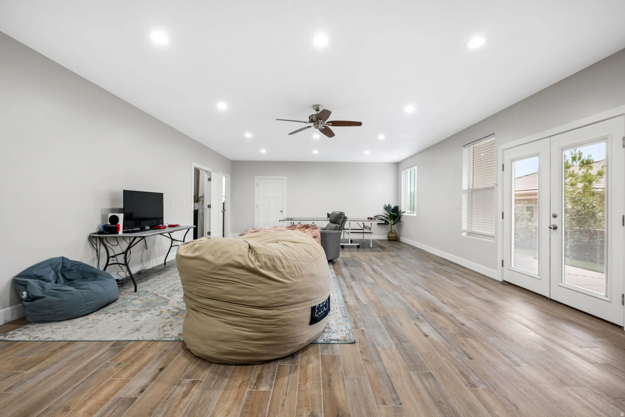 Living area featuring french doors, light wood-type flooring, a ceiling fan, and recessed lighting