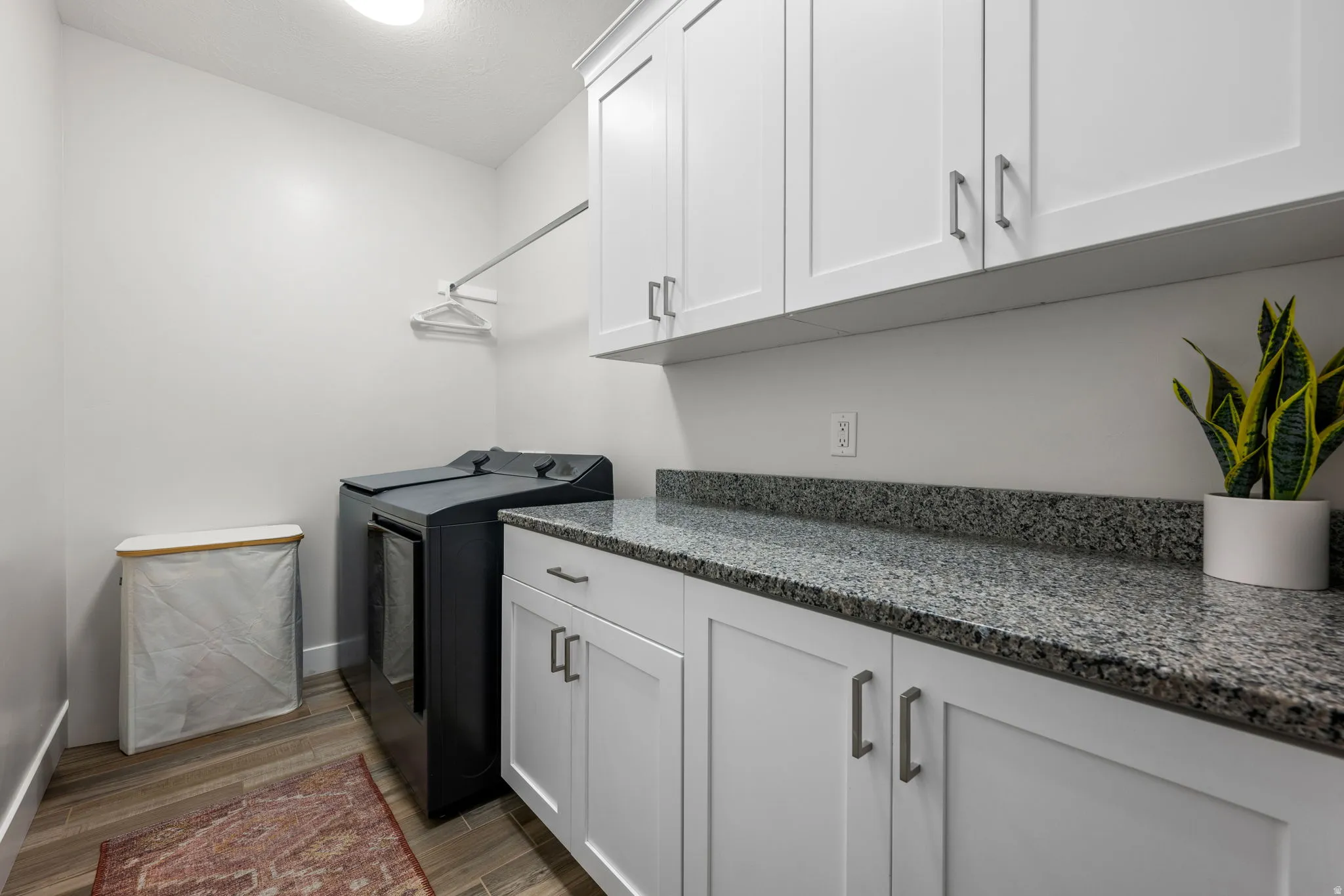 Laundry room with wood tiled floors, washer and clothes dryer, and cabinet space