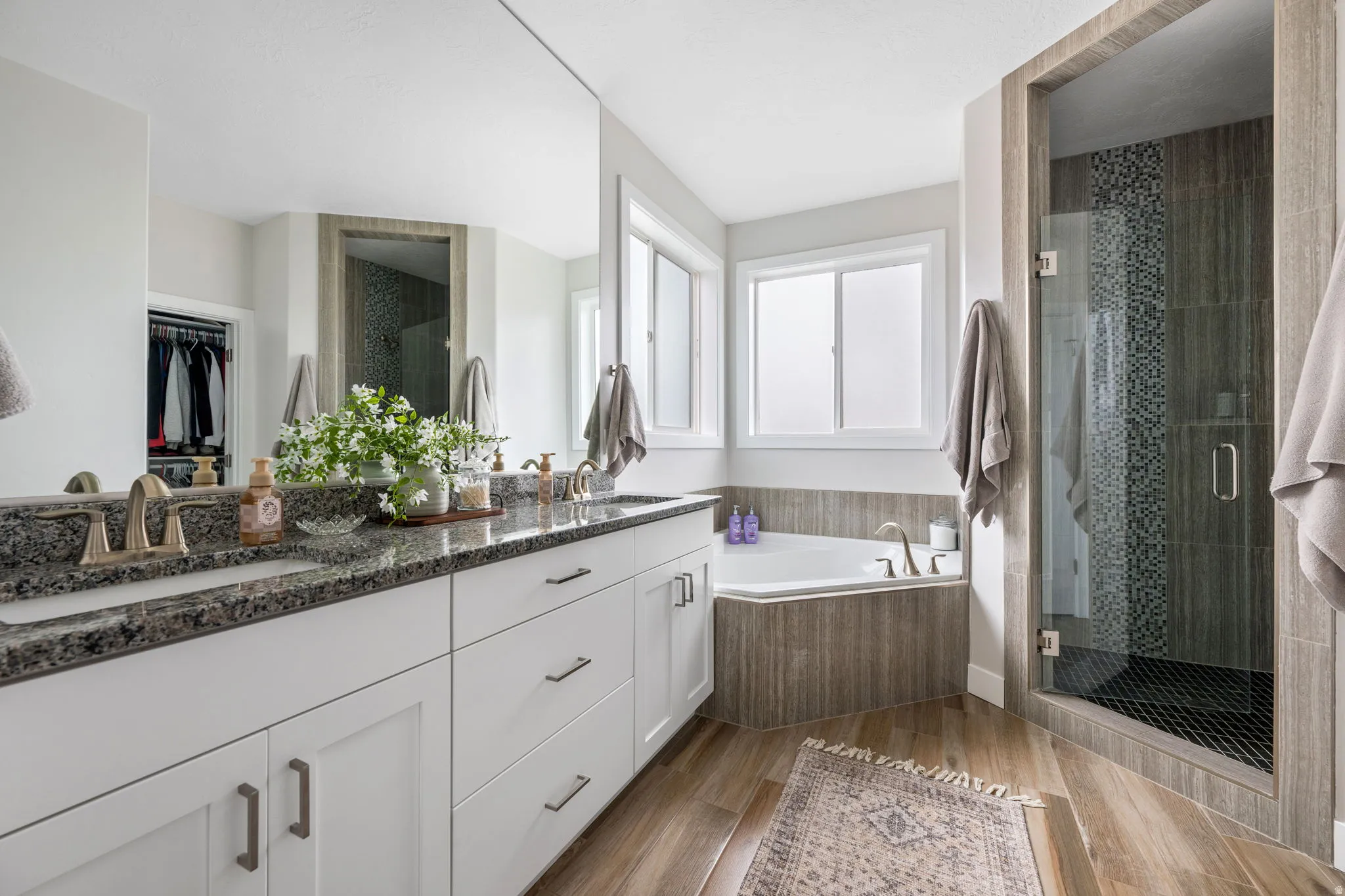 Full bathroom featuring a stall shower, double vanity, a walk in closet, and a bath