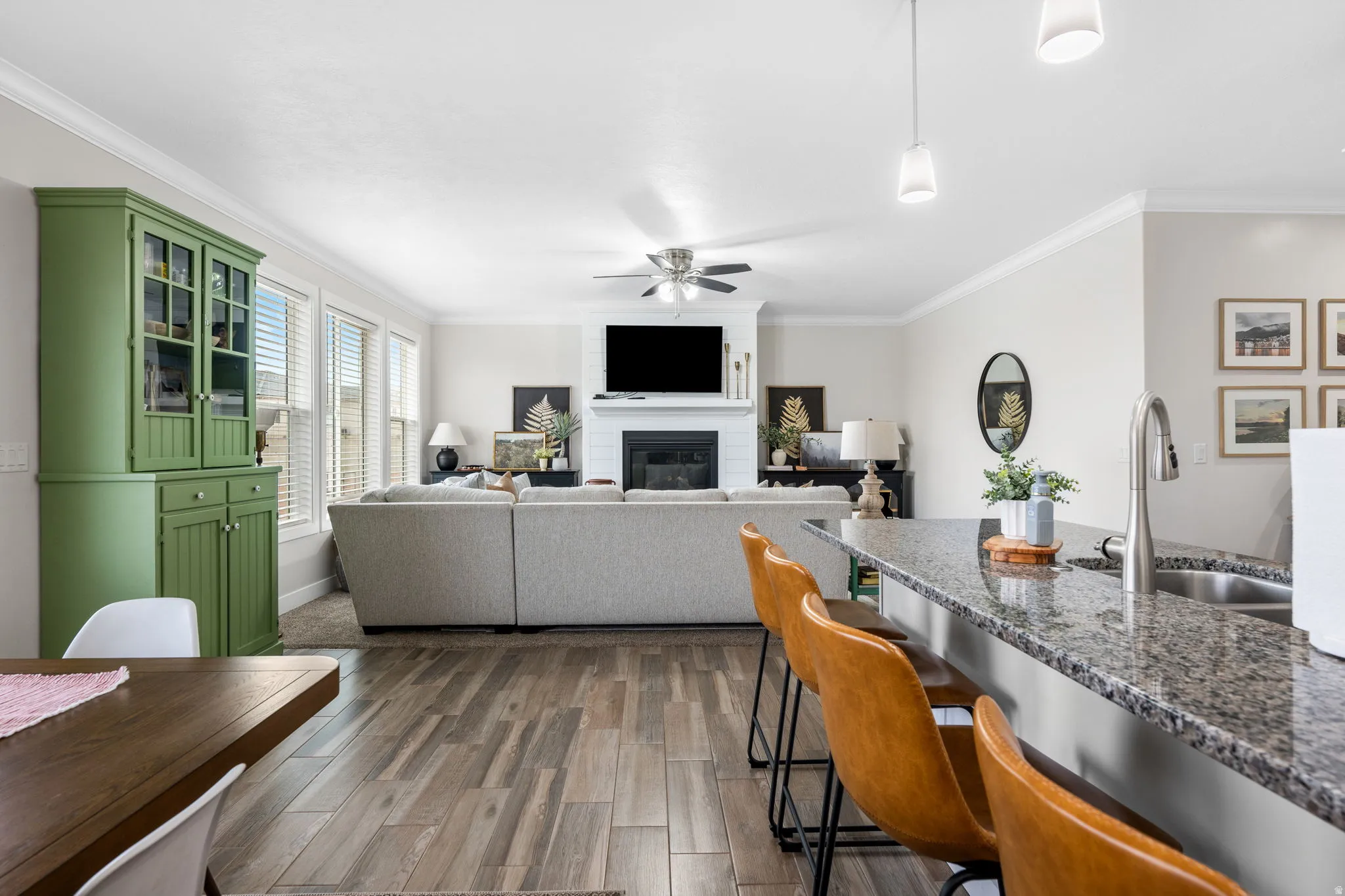 Living area with dark wood-type flooring, a ceiling fan, a fireplace, and crown molding
