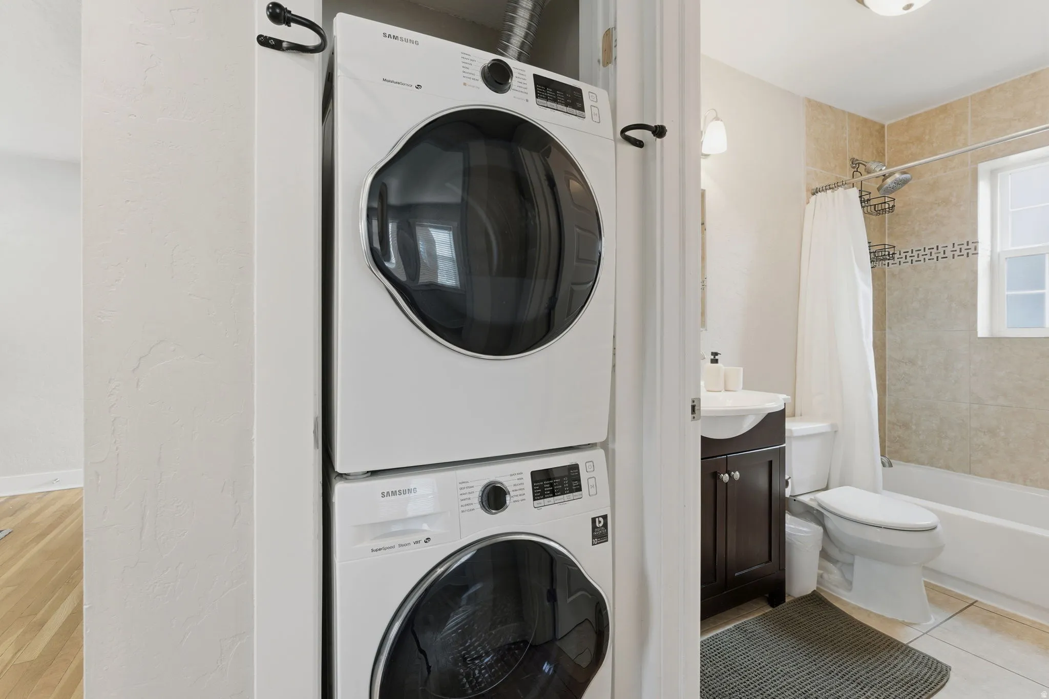 Laundry area featuring stacked washing machine and dryer and light tile patterned floors