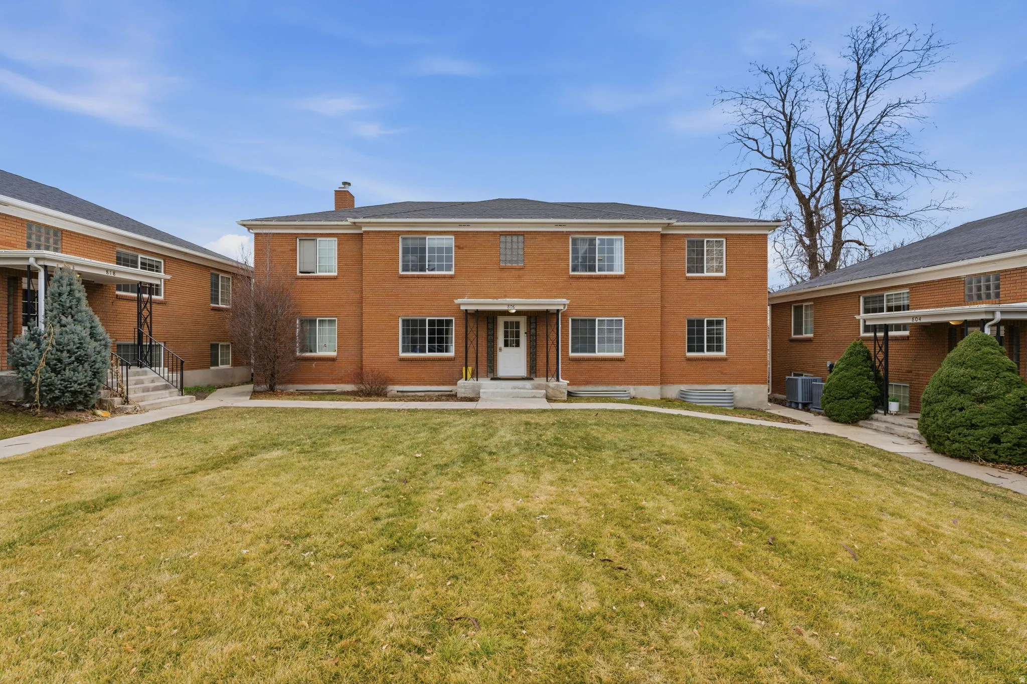 View of front facade with a chimney, a front yard, and brick siding